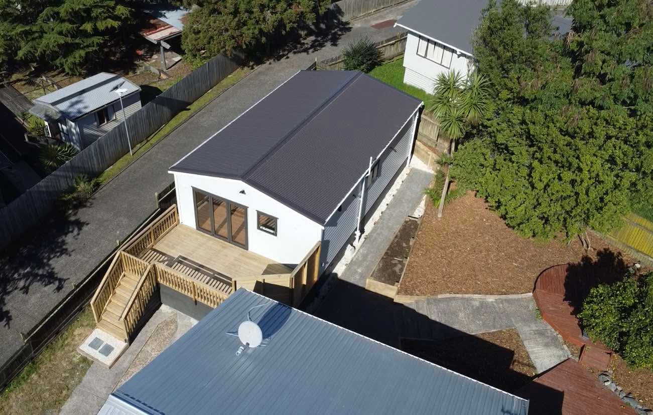 60sqm two-bedroom, one-bathroom minor dwelling with deck, balustrade, privacy screen, retaining wall, garden bed and paving in Auckland