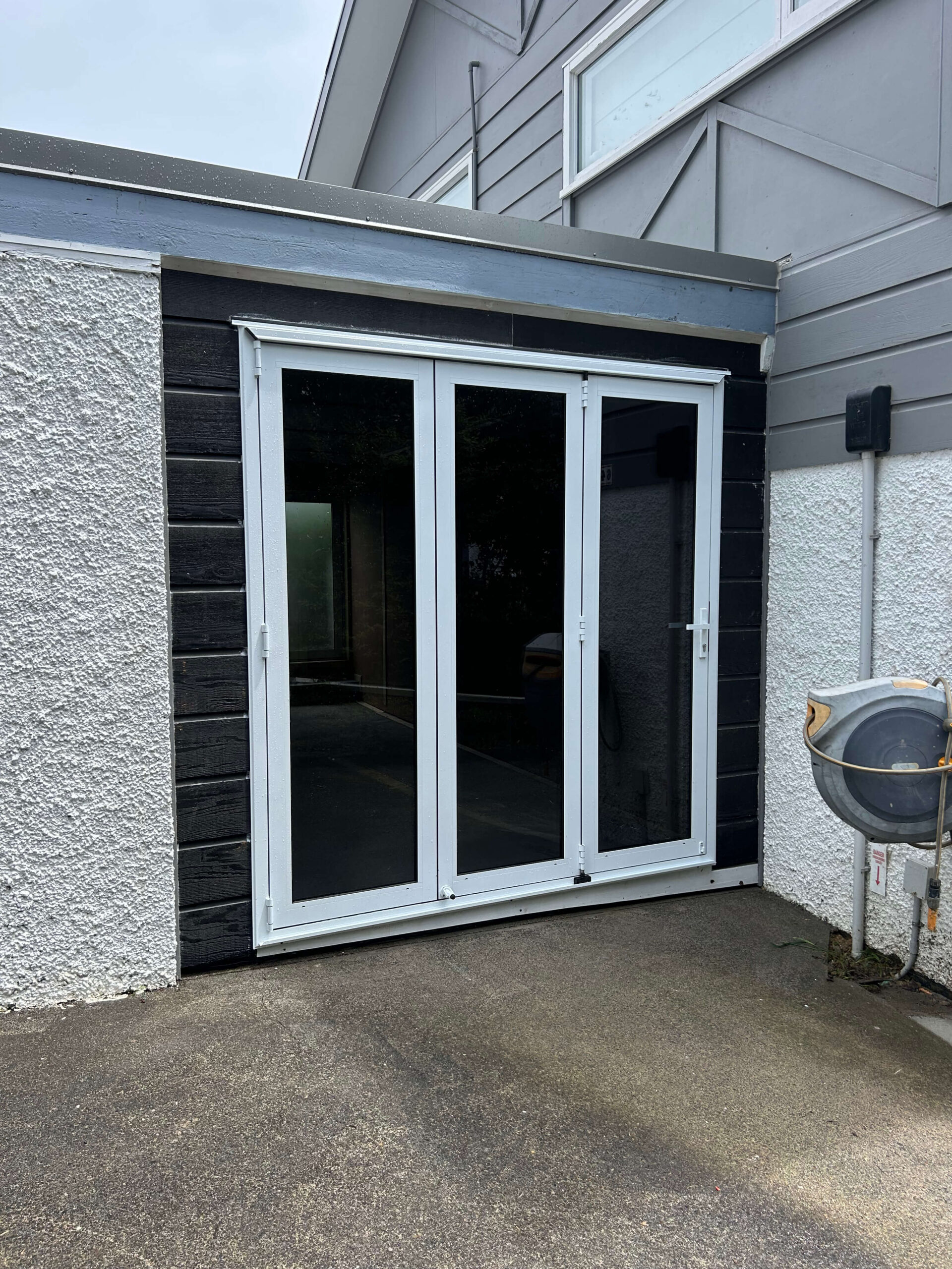 Garage conversion completed in Central Auckland featuring new bifold doors, timber weatherboard cladding and transformed living space.